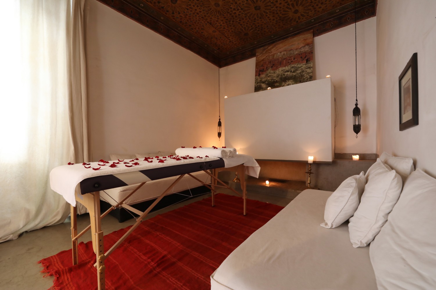 La salle de massage sous son plafond peint : pétales de rose, lanternes et bougies