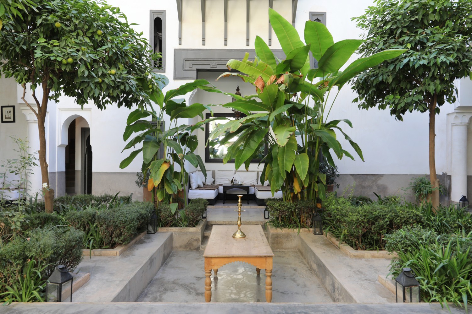 Le patio-jardin et sa table basse devant les salons, à l'ombre des orangers et des bananiers