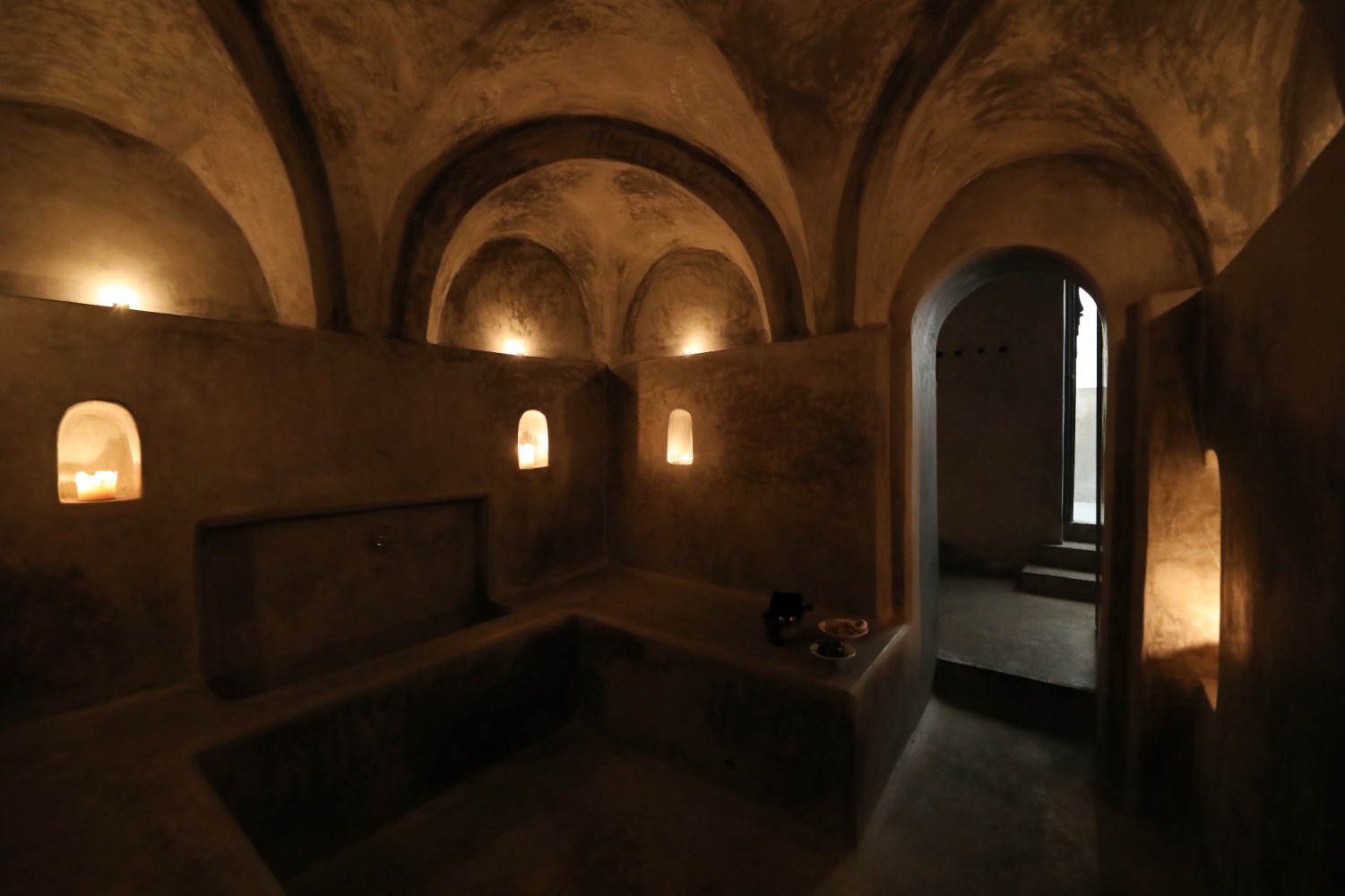 Les voûtes du hammam en tadelakt noir, bougies allumées dans les niches