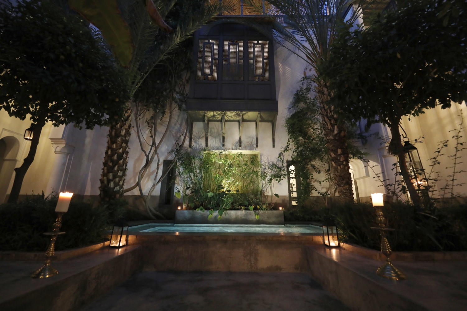 Le bassin du patio la nuit, entouré de bougies et de chandeliers de laiton